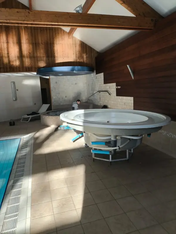Jacuzzi rond en cours d'installation près d'une piscine intérieure