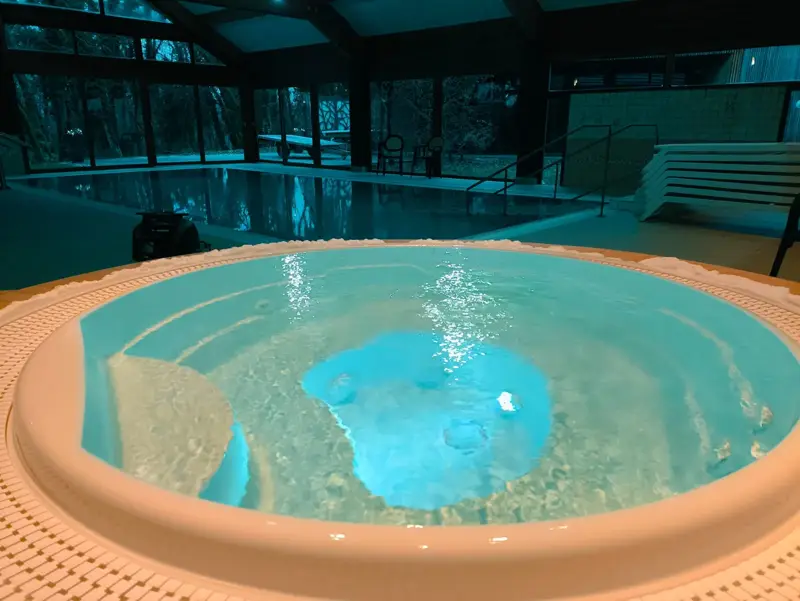 Piscine intérieure et jacuzzi rond en ambiance nocturne